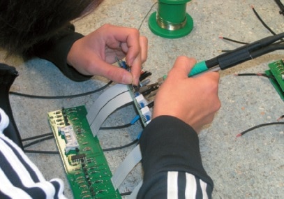 Ein Flachbandkabel wird per Hand eingelötet.